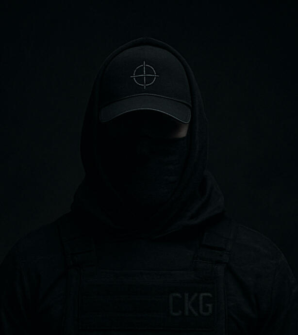 C.K. Grady C.K. Grady: anonymous figure in black, wearing a ball cap marked with a sniper crosshair and a hoodie labelled "CKG". His face is mostly obscured by shadows and a tactical buff, revealing only his eyes - focused and unreadable. The image embodies stealth,